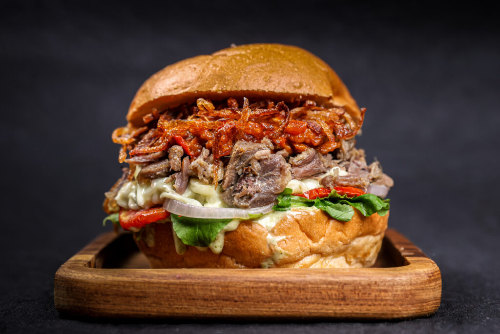 Slow Cooked Mutton Burger with spicy jalapeno green chilli sauce, crispy onions and Zaalouk spread – Tavora Bandra West