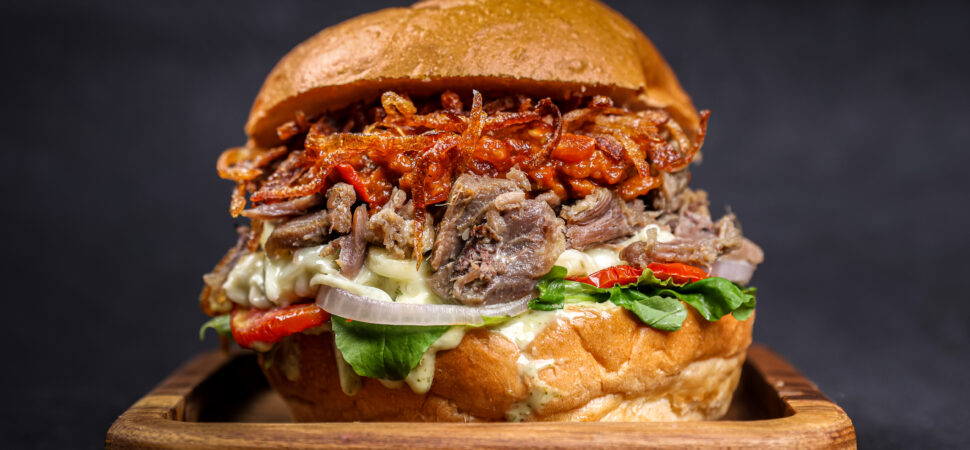 Slow Cooked Mutton Burger with spicy jalapeno green chilli sauce, crispy onions and Zaalouk spread – Tavora Bandra West